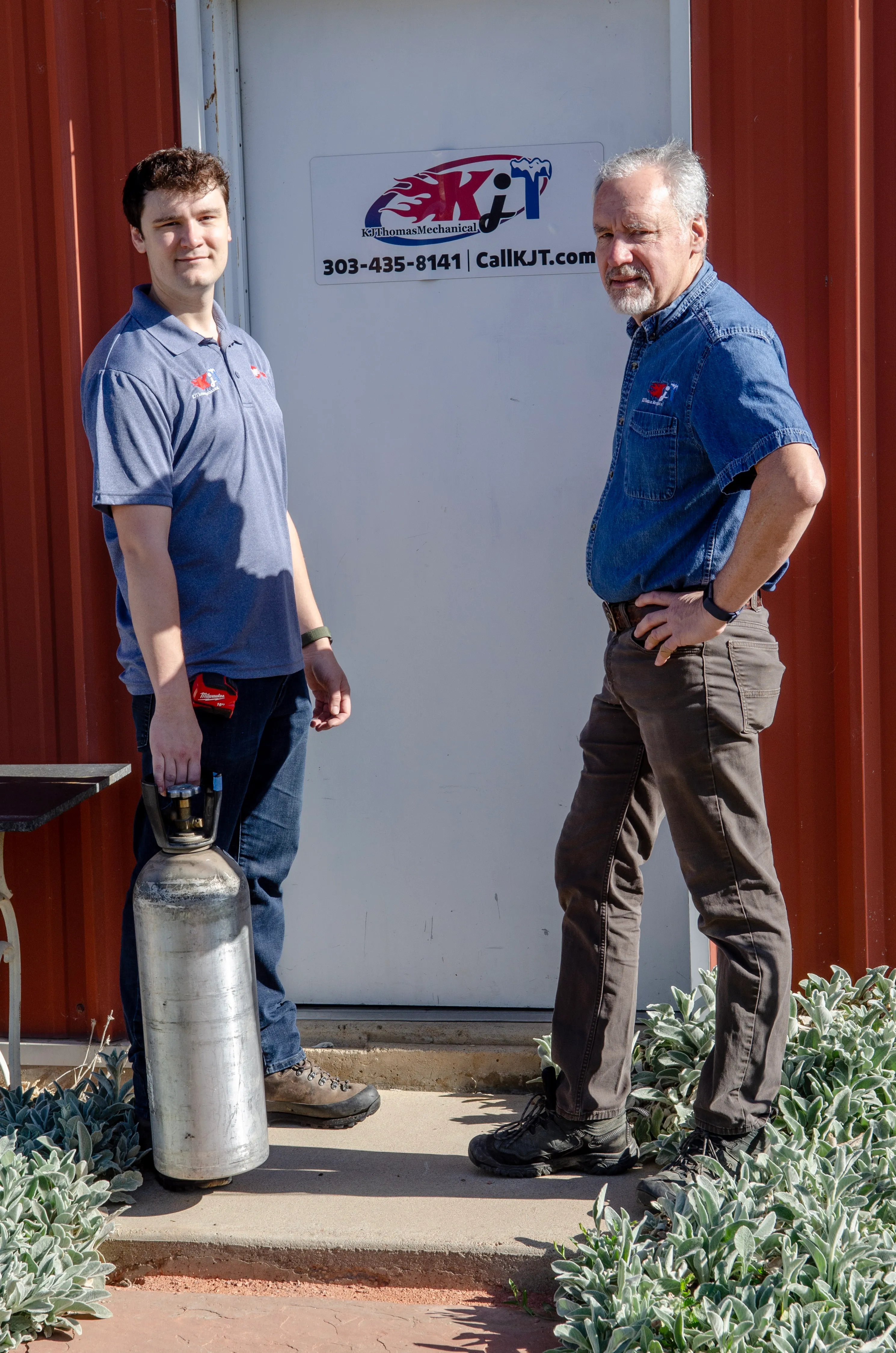 Karl Thomas and a KJ Thomas Mechanical team member standing by the shop door.