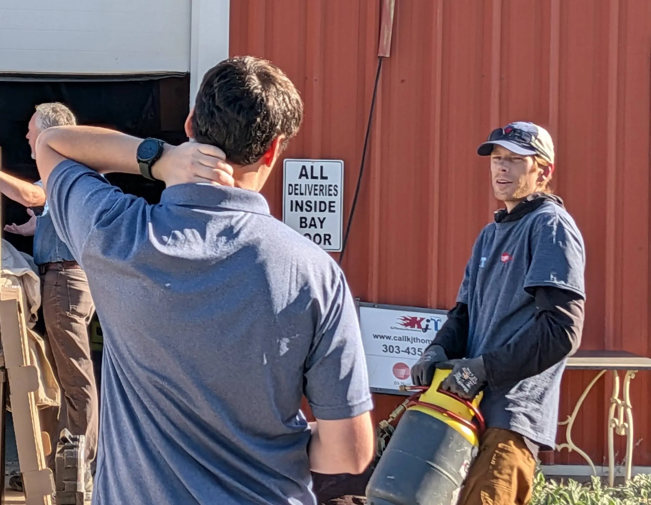 KJ Thomas Mechanical team members talking through equipment outside the shop.